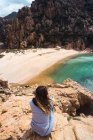 Frau sitzt auf Felsen am Meer und blickt auf die Aussicht — Stockfoto