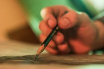 Mão fechada de pessoa irreconhecível que desenha com lápis — Fotografia de Stock