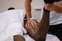 Физиотерапевт лечит человека, используя оборудование для радиотерапии — стоковое фото