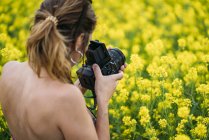 Крупним планом жінка з ретро камерою фотографується в природі з жовтими квітами — стокове фото