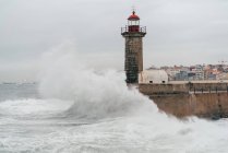 Leuchtturm auf Pier am welligen Ozean, Porto, Portugal — Stockfoto
