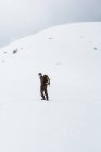 Turista con zaino arrampicata su montagna innevata — Foto stock