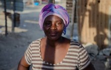 АНГОЛА - АФРИКА - 5 апреля 2018 года - чёрная женщина с фиолетовым головным убором, стоящая и смотрящая в камеру — стоковое фото