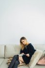 Jovem mulher ler livro no sofá em casa — Fotografia de Stock