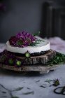 Вкусный торт украшен свежими цветами на деревянном блюде — стоковое фото