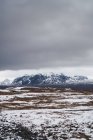 Ruhiges schneebedecktes Tal mit Bergen unter bewölktem Himmel, Island — Stockfoto