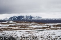 Ruhiges schneebedecktes Tal mit Bergen unter bewölktem Himmel, Island — Stockfoto