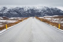 Estrada no campo com montanhas cobertas de neve no fundo, Islândia — Fotografia de Stock