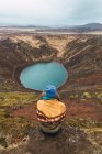 Donna seduta sulla roccia contro il lago in montagna e guardando la vista, Islanda — Foto stock