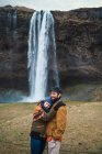 Paar steht gemeinsam vor Wasserfall — Stockfoto
