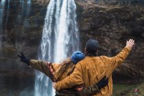 Casal em pé na frente da cachoeira juntos — Fotografia de Stock