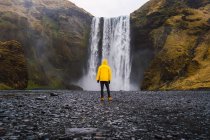 Uomo in piedi vicino alla cascata — Foto stock