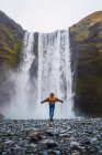 Donna in piedi di fronte alla cascata con le braccia tese — Foto stock