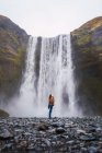 Жінка стоїть перед водоспадом з простягнутими руками — стокове фото