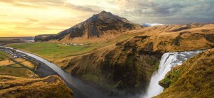 Gorgeous landscape with texture mountains and waterfall under cloudy sky, Iceland — Stock Photo