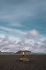 Анонімний чоловік стоїть на скелі серед скелястої рівнини з горами за хмарним небом, Ісландія.. — стокове фото