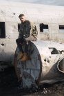 Человек, сидящий на старом разрушенном самолете — стоковое фото