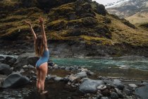 Giovane donna in costume da bagno in piedi nel fiume di montagna — Foto stock