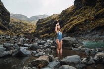 Giovane donna in costume da bagno in piedi nel fiume di montagna — Foto stock