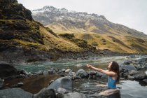 Jovem mulher sentada no rio da montanha — Fotografia de Stock