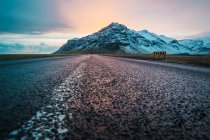 Estrada no campo e montanha nevada ao nascer do sol — Fotografia de Stock