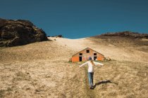 Woman standing on hill near wooden barn — Stock Photo