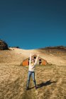 Woman with arms up standing on hill near wooden barn — Stock Photo