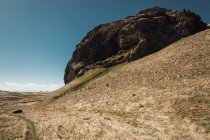 Riesiger Felsen in Hügeln unter blauem Himmel, Island — Stockfoto