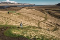 Mujer de pie en el valle con montañas y lago en el fondo, Islandia - foto de stock