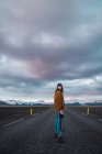 Woman standing on road in countryside with camera and looking at camera — Stock Photo