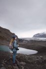 Жінка з фотоапаратом і рюкзаком насолоджується видом на засніжені гори — стокове фото