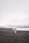 Donna con zaino a piedi sulla costa invernale — Foto stock