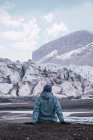 Женщина, сидящая в снежных горах зимой и наслаждающаяся видом — стоковое фото