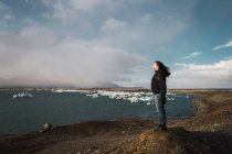 Donna in piedi sul freddo paesaggio marino e guardando la vista — Foto stock