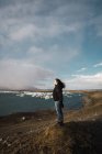 Donna in piedi sul freddo paesaggio marino e guardando la vista — Foto stock
