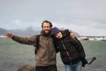 Coppia ridente in piedi al lago freddo in natura — Foto stock