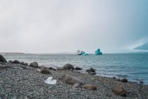 Eisklumpen im Wasser und Strand mit Kieseln und Felsen, skaftafell, vatnajokull, Island — Stockfoto