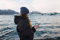 Frau benutzt Smartphone am kalten Strand — Stockfoto
