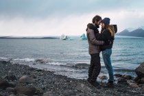 Couple aimant debout sur le paysage marin froid face à face — Photo de stock