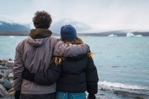 Любящая пара, стоящая на холодном море и смотрящая на вид — стоковое фото