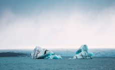 Vista lejana de glaciares en agua azul del océano - foto de stock