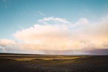 Silenziosa pianura verde remota sotto nuvole incandescenti nel cielo blu, Islanda — Foto stock