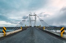 Route asphaltée et pont suspendu sous les nuages sombres, Islande — Photo de stock