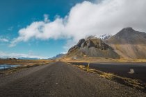 Paisagem de montanhas remotas e estrada e céu azul com nuvens, Islândia — Fotografia de Stock