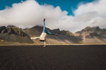 Mulher fazendo suporte de mão em uma mão com montanhas no fundo, Islândia — Fotografia de Stock