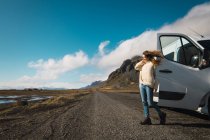 Donna in piedi vicino autobus viaggiante in montagna, Islanda — Foto stock