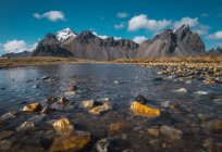 Freddo ruscello di cristallo tra rocce e montagne rocciose sullo sfondo, Islanda — Foto stock