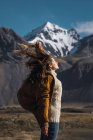 Mulher com cabelo voando em pé vento com montanhas no fundo — Fotografia de Stock