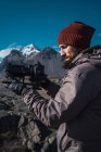 Bearded man holding professional camera while standing in sunlight of mountains — Stock Photo