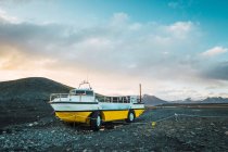 Weiß-gelbes Boot mit Rädern, das auf einem steinigen Hügel steht, skaftafell, vatnajokull, Island — Stockfoto